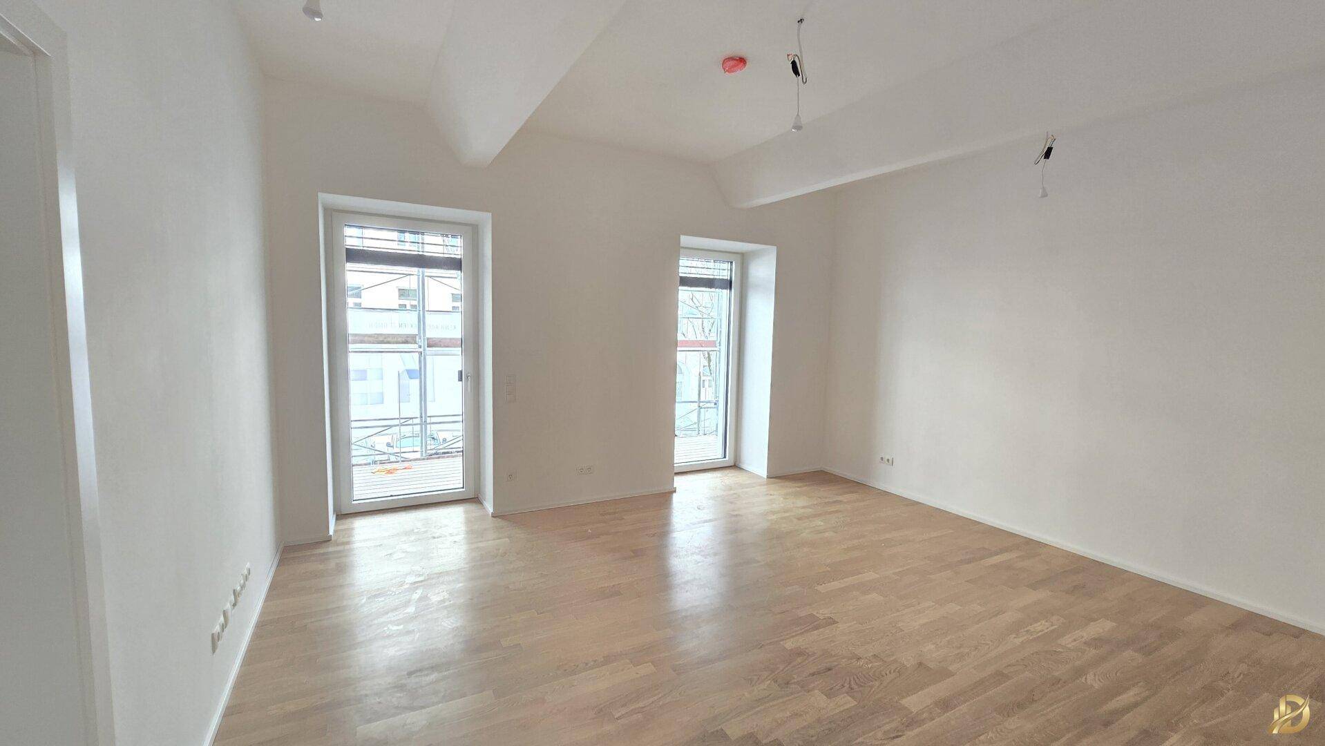 Lichtdurchflutetes Zimmer mit hellem Parkettboden und hohen Decken, ideal für Wohnzwecke.