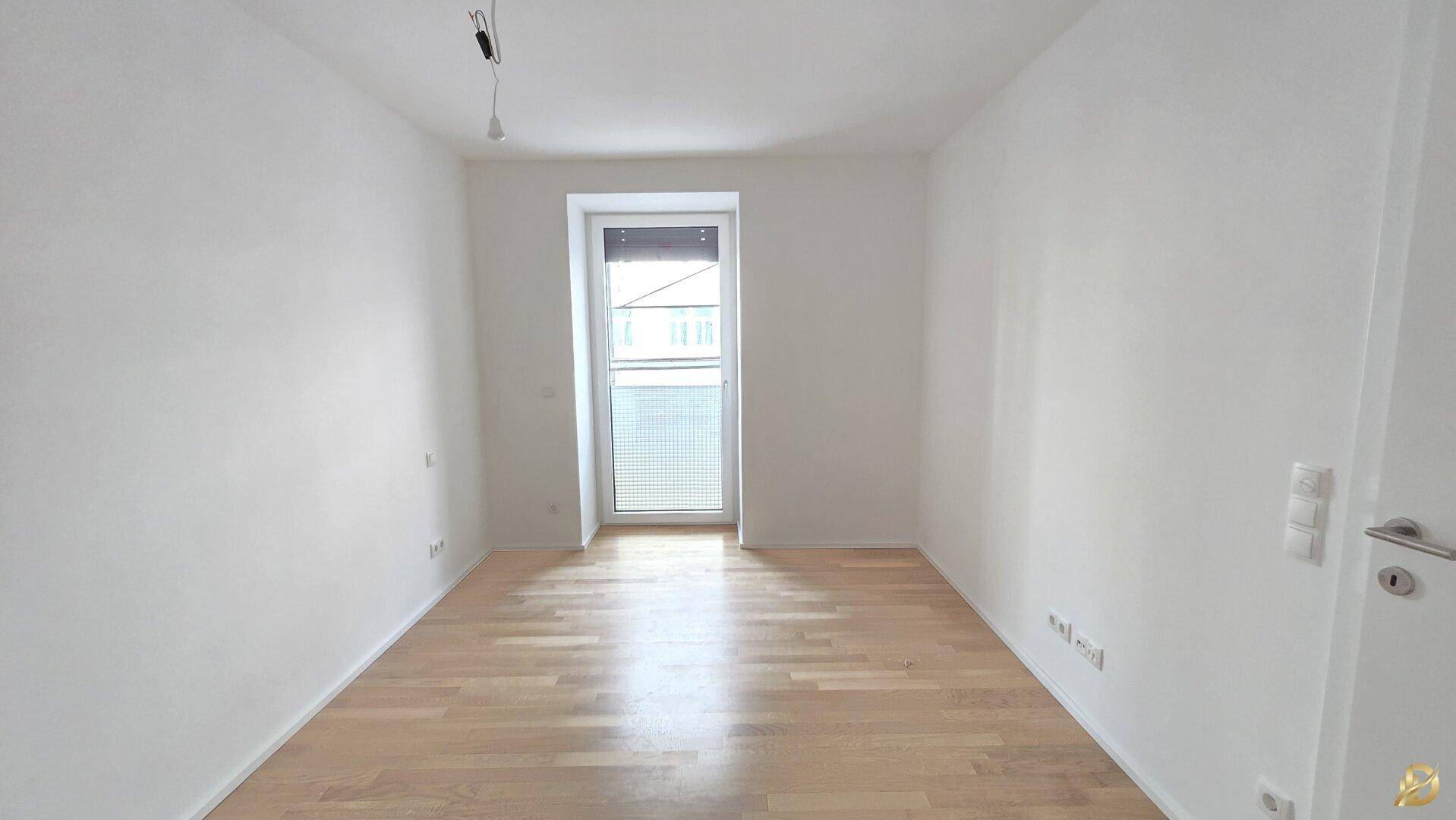 Ruhiges Schlafzimmer mit hellem Parkett und großem Fenster, ideal zum Entspannen.