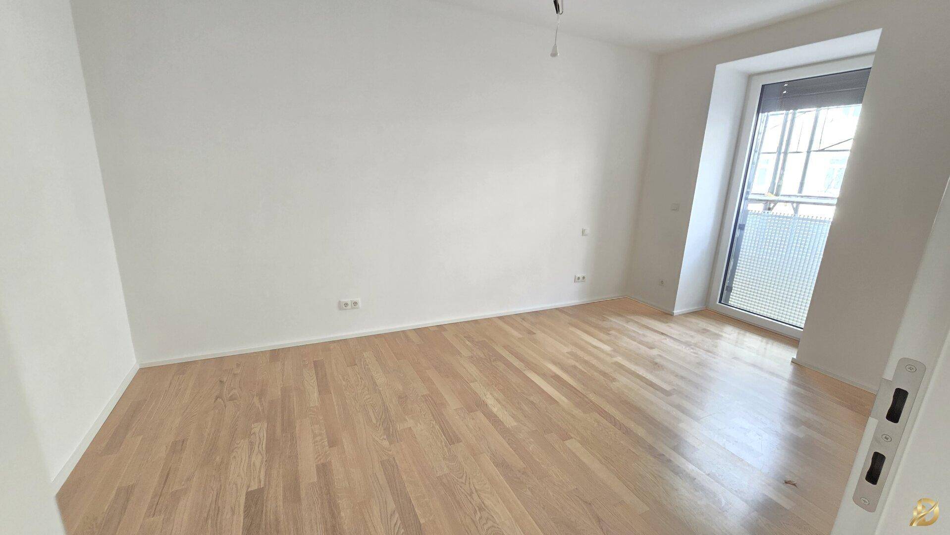 Helles Schlafzimmer mit Parkettboden und großem Fenster, bietet viel Tageslicht.