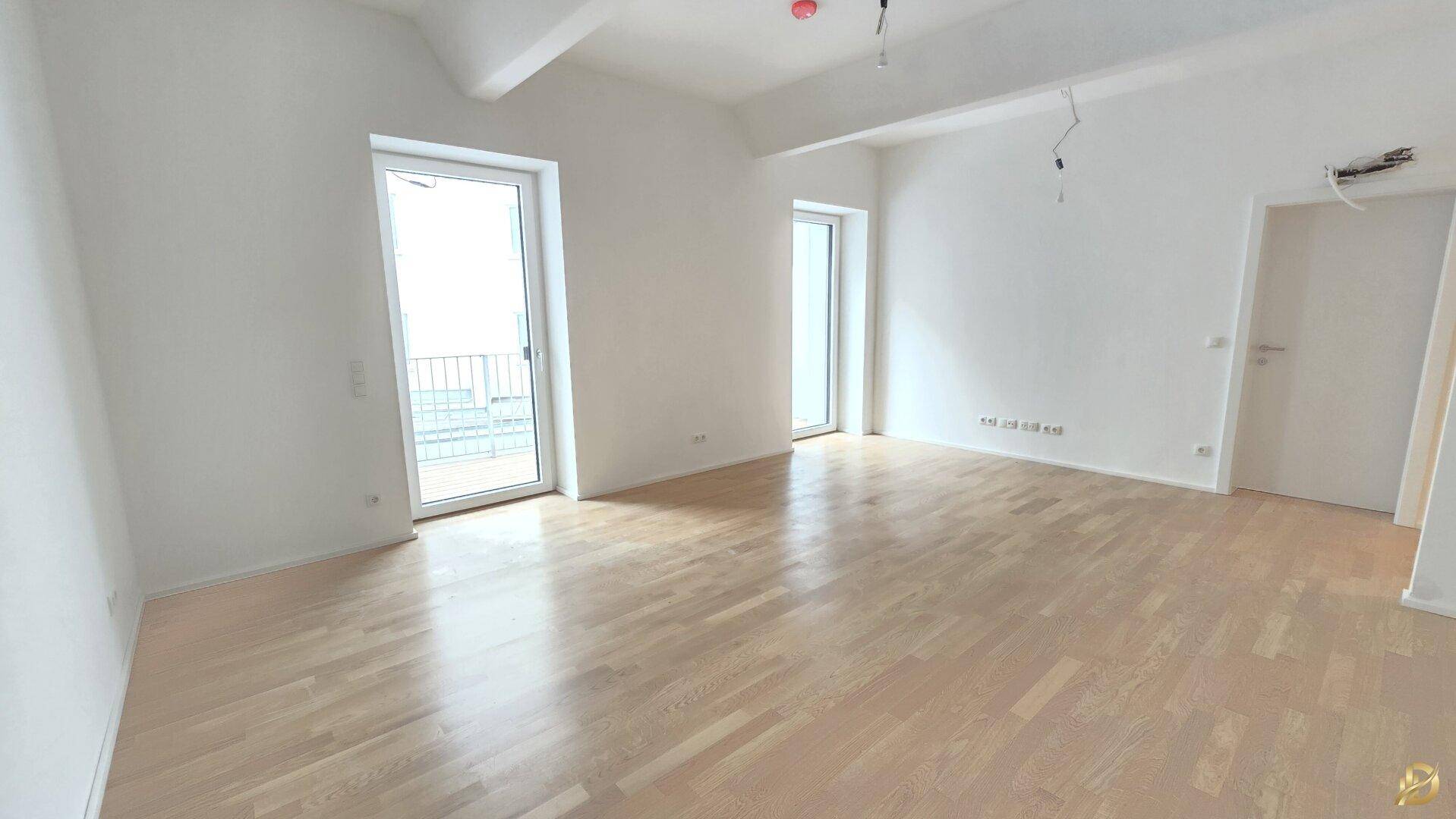 Helles, unmöbliertes Zimmer mit Parkettboden und zwei großen Fenstern.