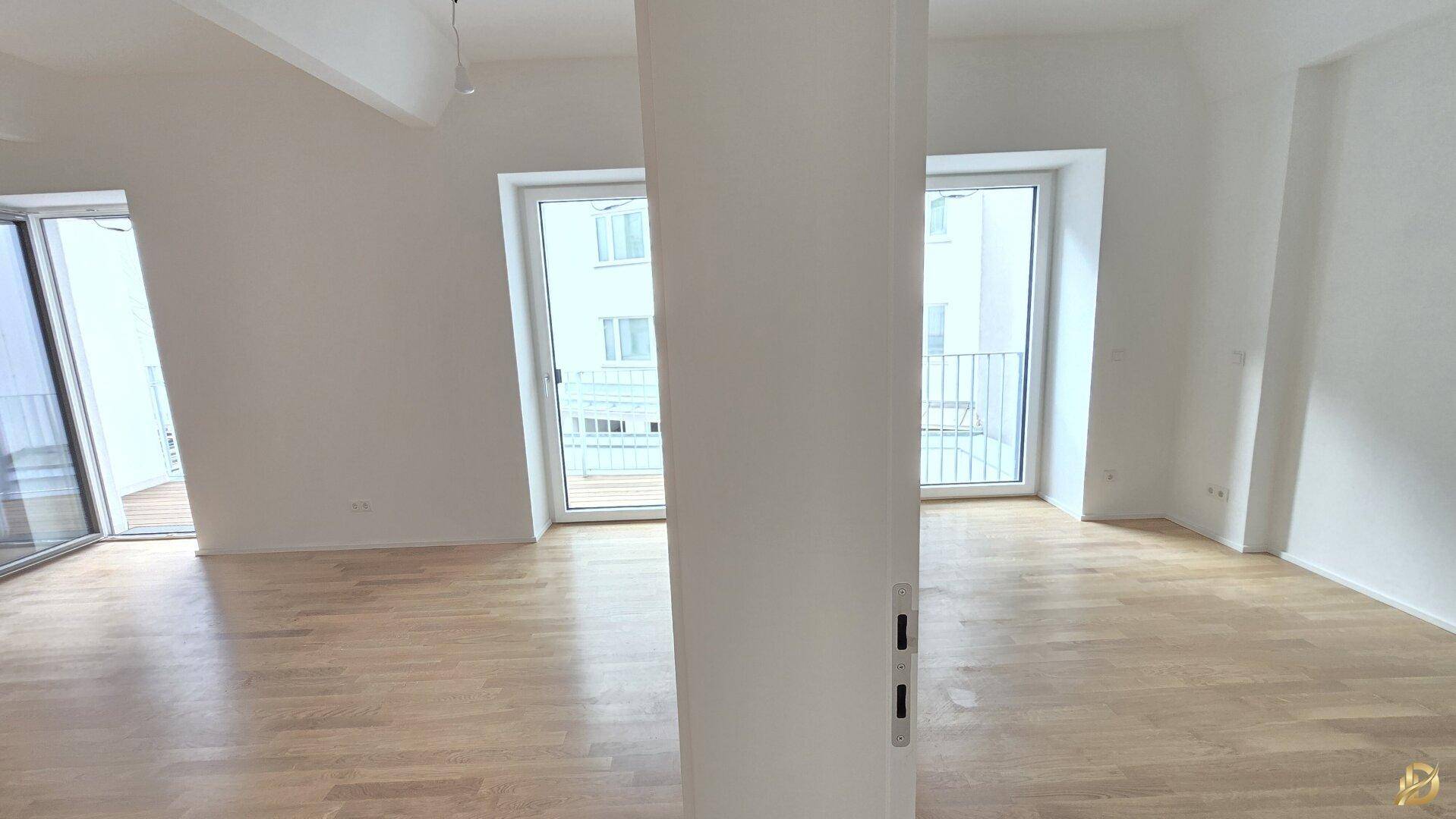 Helles Zimmer mit Parkettboden und zwei französischen Balkonen.