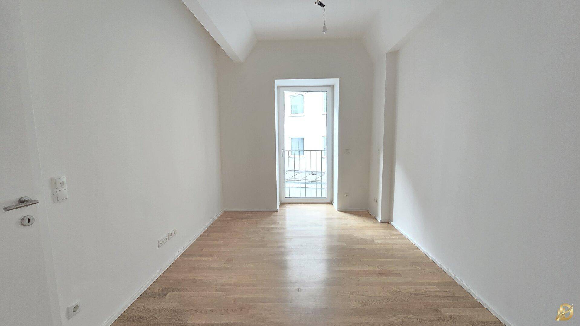 Helles Schlafzimmer mit Parkettboden und einem französischen Balkon.