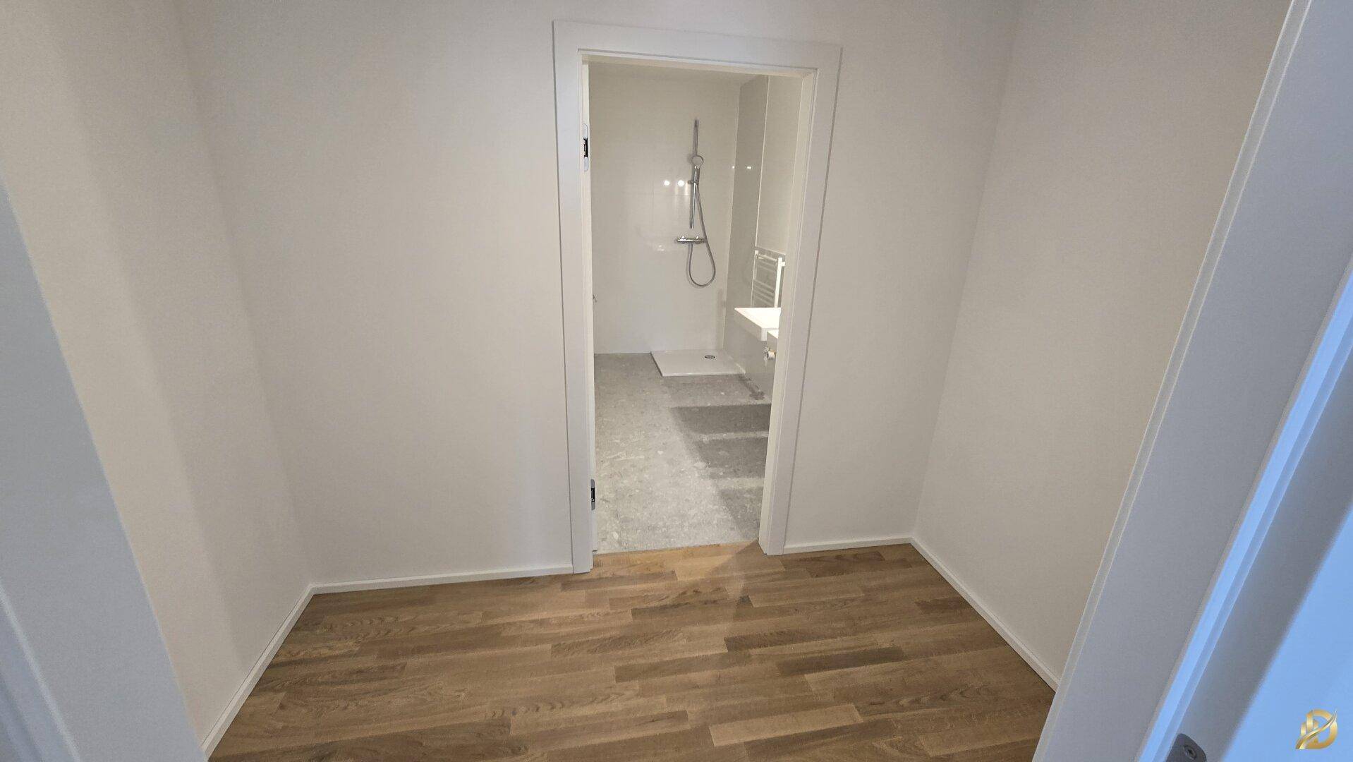 Flur mit Parkettboden, der zu einem modernen Badezimmer führt.