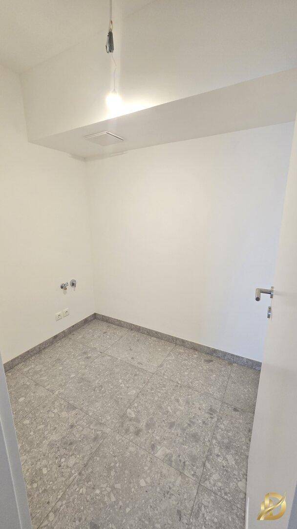 Hauswirtschaftsraum mit Fliesenboden und Anschlüssen für Waschmaschine.