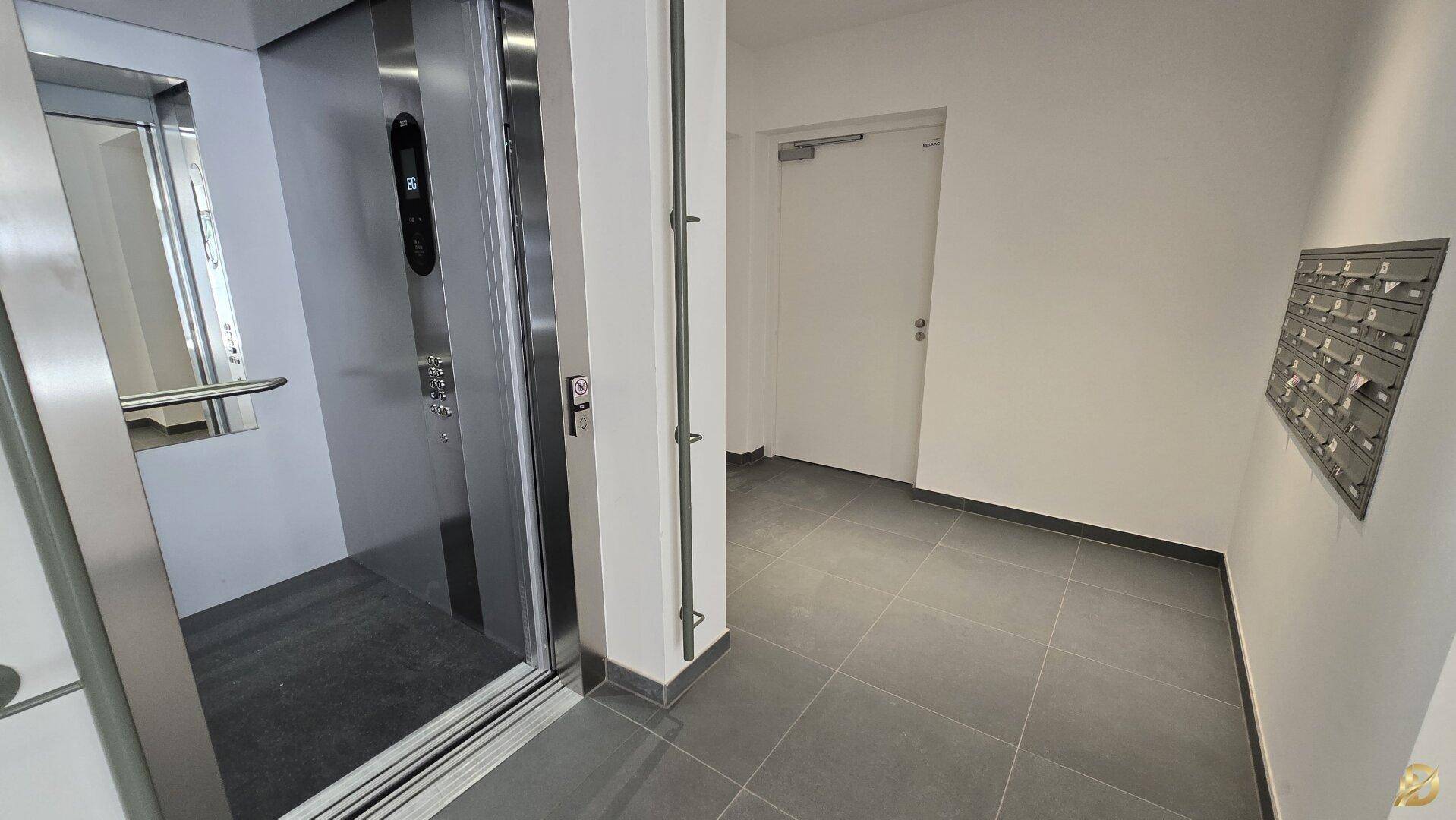 Heller Eingangsbereich mit Aufzug und Briefkästen im Mehrfamilienhaus.