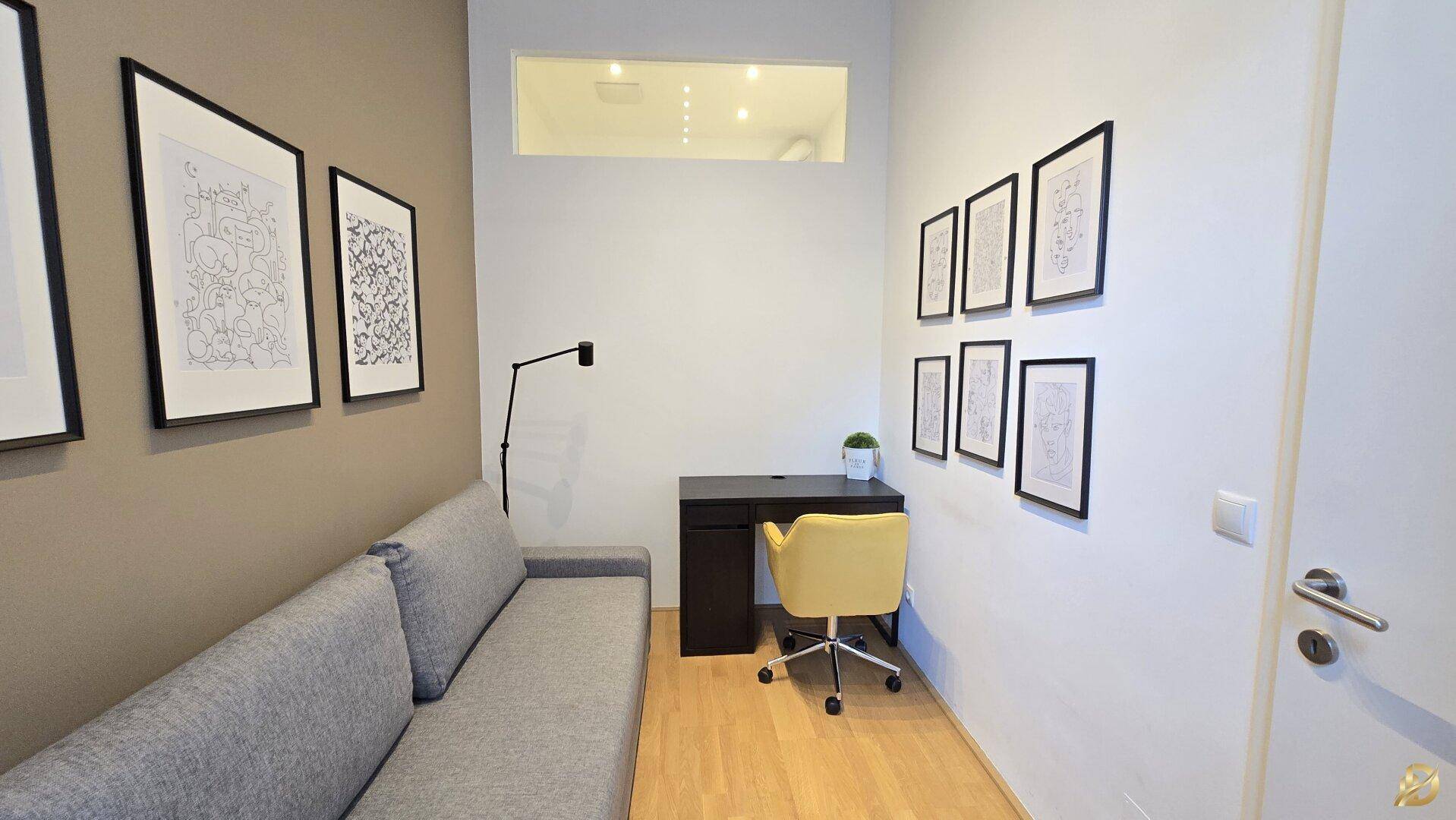 Funktionaler Arbeitsbereich mit Schreibtisch, bequemem Sofa und dekorativen Bildern.