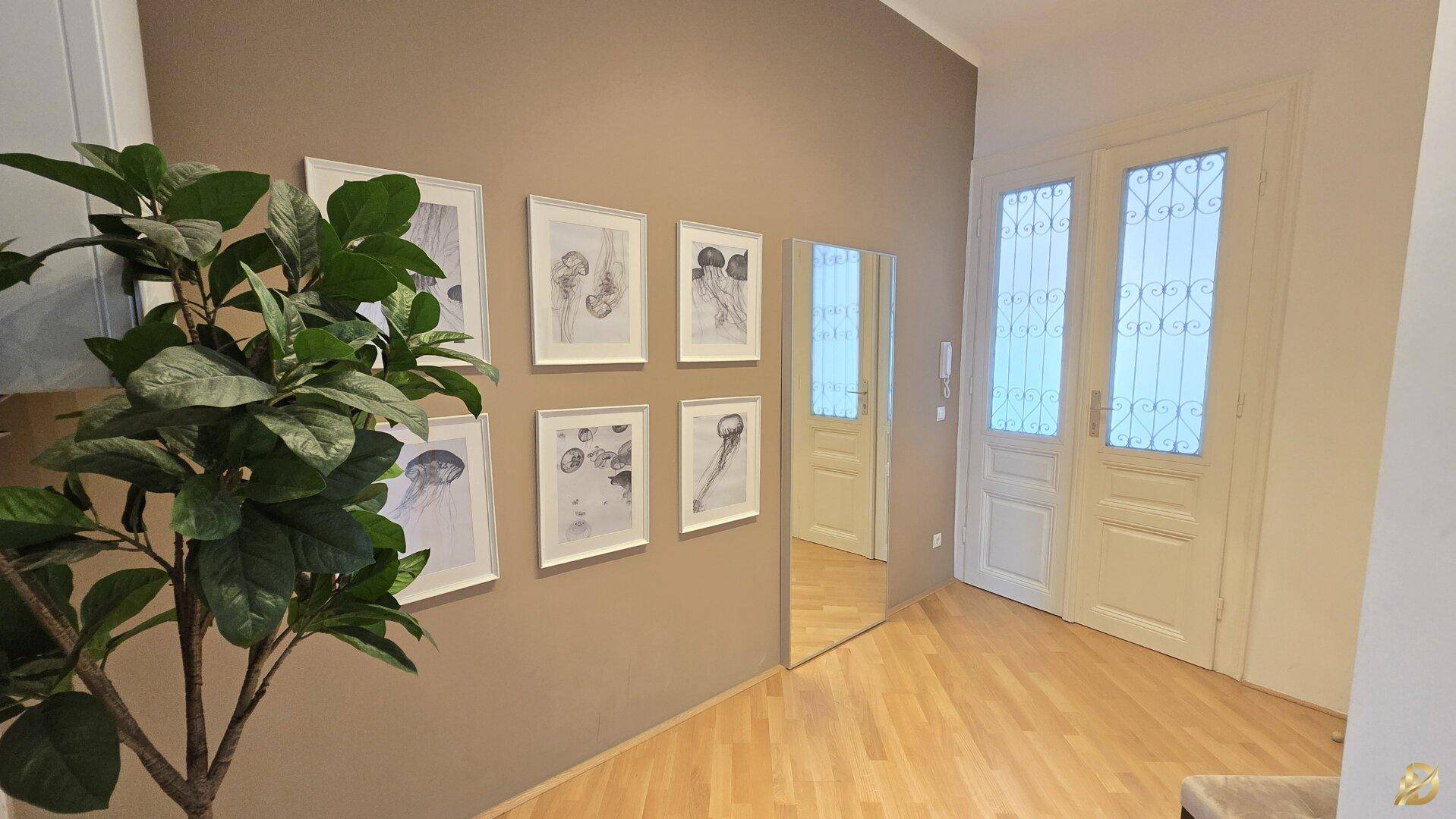 Heller Flur mit Holzboden, dekorativen Bildern und eleganten Doppeltüren mit Glaseinsätzen.