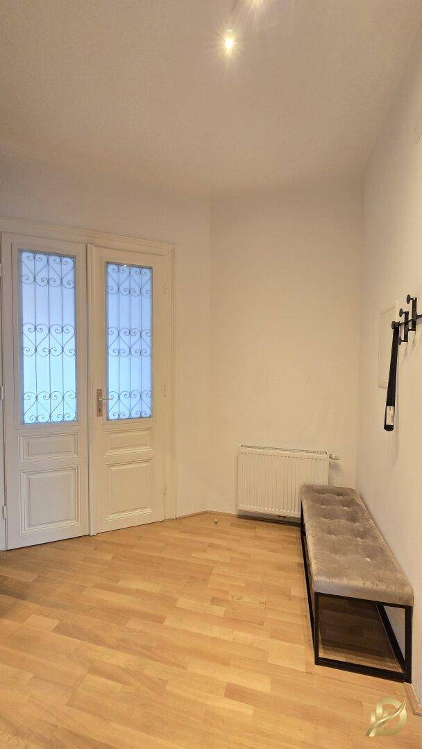 Eingangsbereich mit Holzboden, einer gepolsterten Sitzbank und klassischen Doppeltüren.