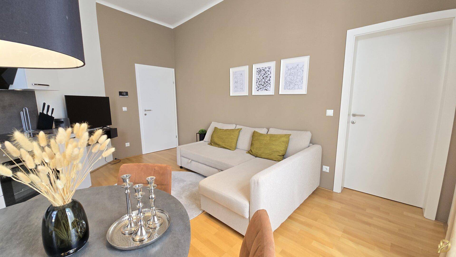 Gemütliche Sofaecke mit dekorativen Bildern an der Wand und Zugang zu weiteren Räumen.