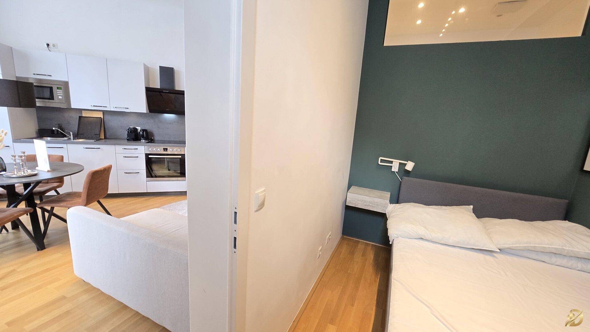 Übergangsbereich zwischen Wohnzimmer und Schlafzimmer mit Holzboden und moderner Einrichtung.