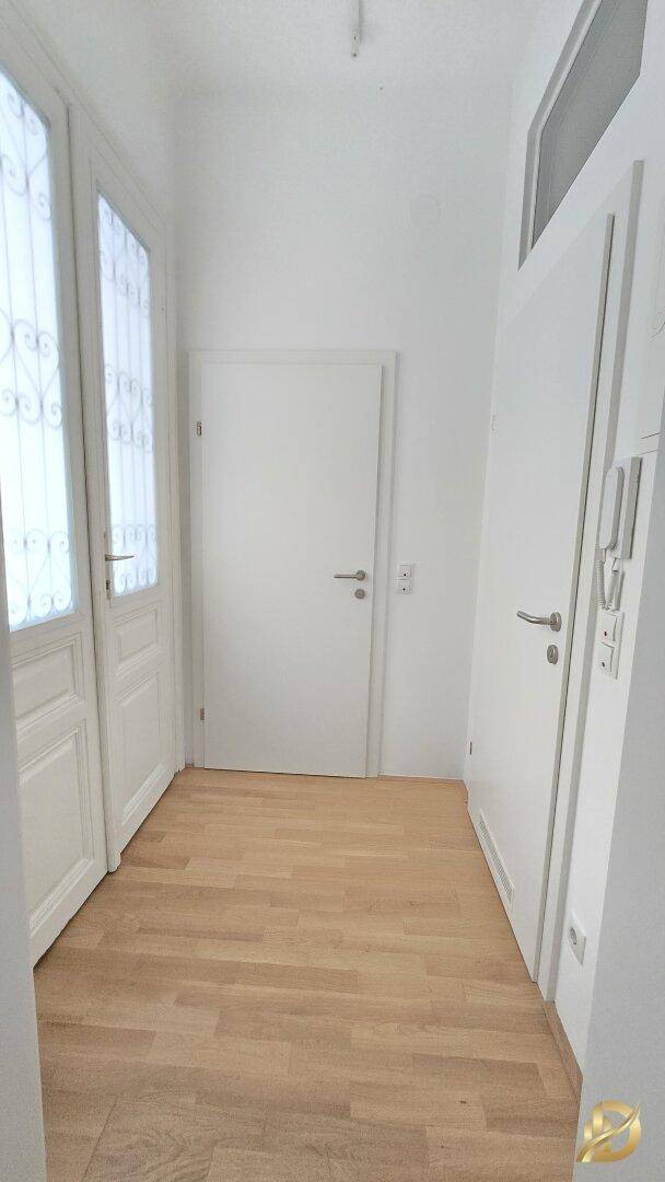 Heller Flur mit Holzboden und weißen Türen, einladender Eingangsbereich.