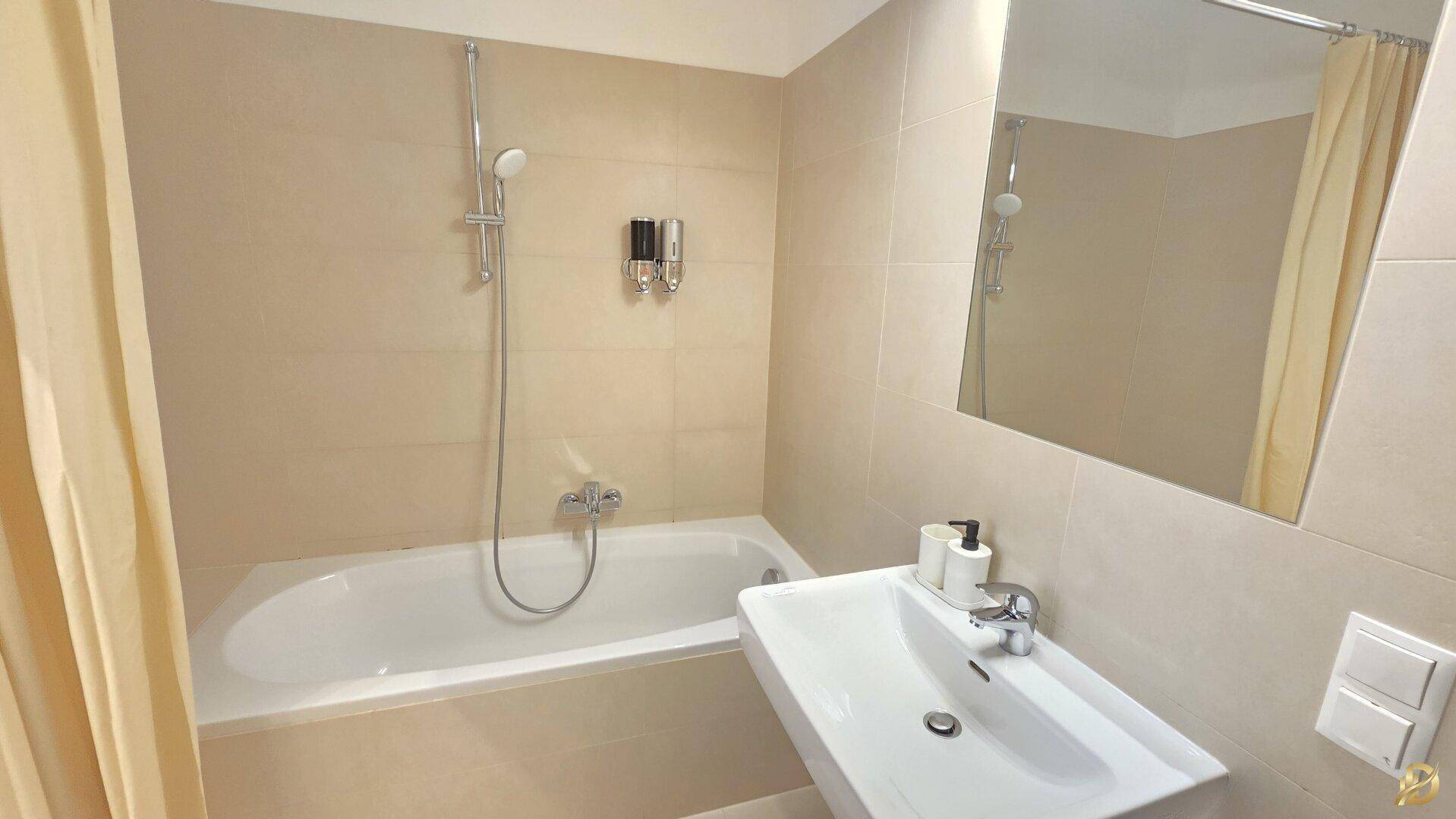 Badezimmer mit Badewanne, Duschfunktion und modernem Waschbecken, beige Fliesen.