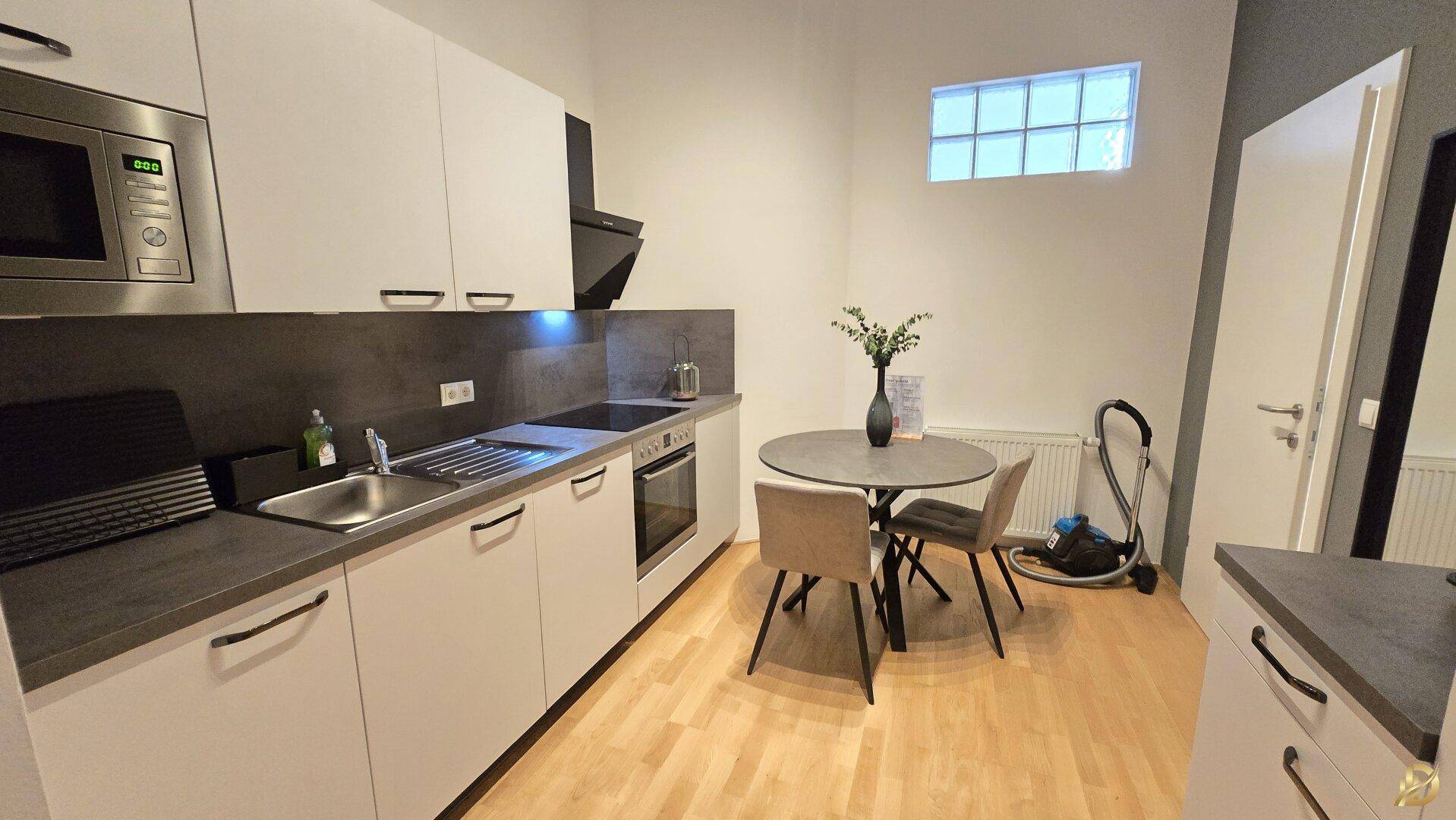 Moderne Einbauküche mit Essbereich, hellen Schränken und integrierten Geräten.
