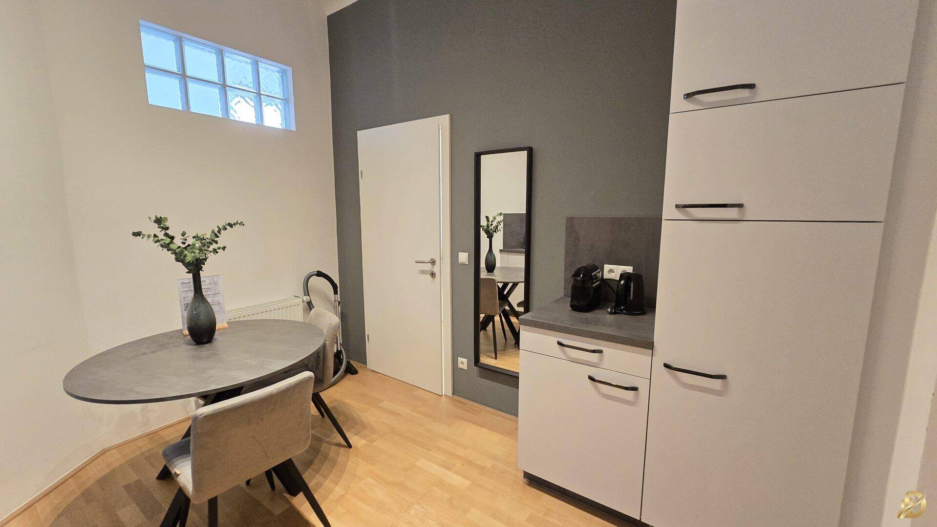Helle Küche mit Essbereich, weißen Schränken und dunkler Arbeitsplatte, moderner Stil.