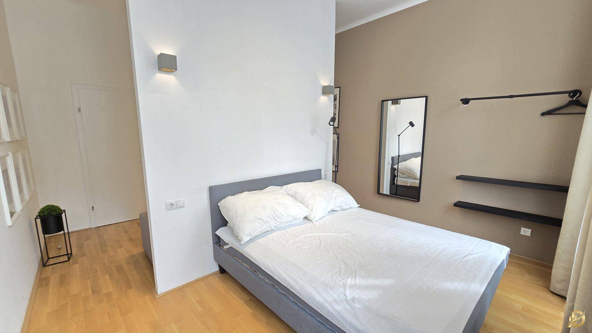 Helles Schlafzimmer mit Doppelbett, Spiegel und Wandleuchten, moderne Einrichtung.