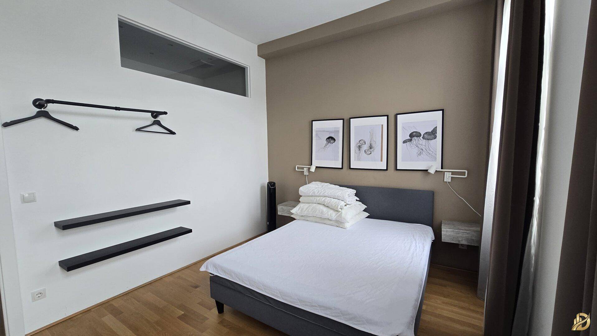 Schlafzimmer mit Doppelbett, offener Garderobenlösung und einem Oberlicht für zusätzliche Helligkeit.