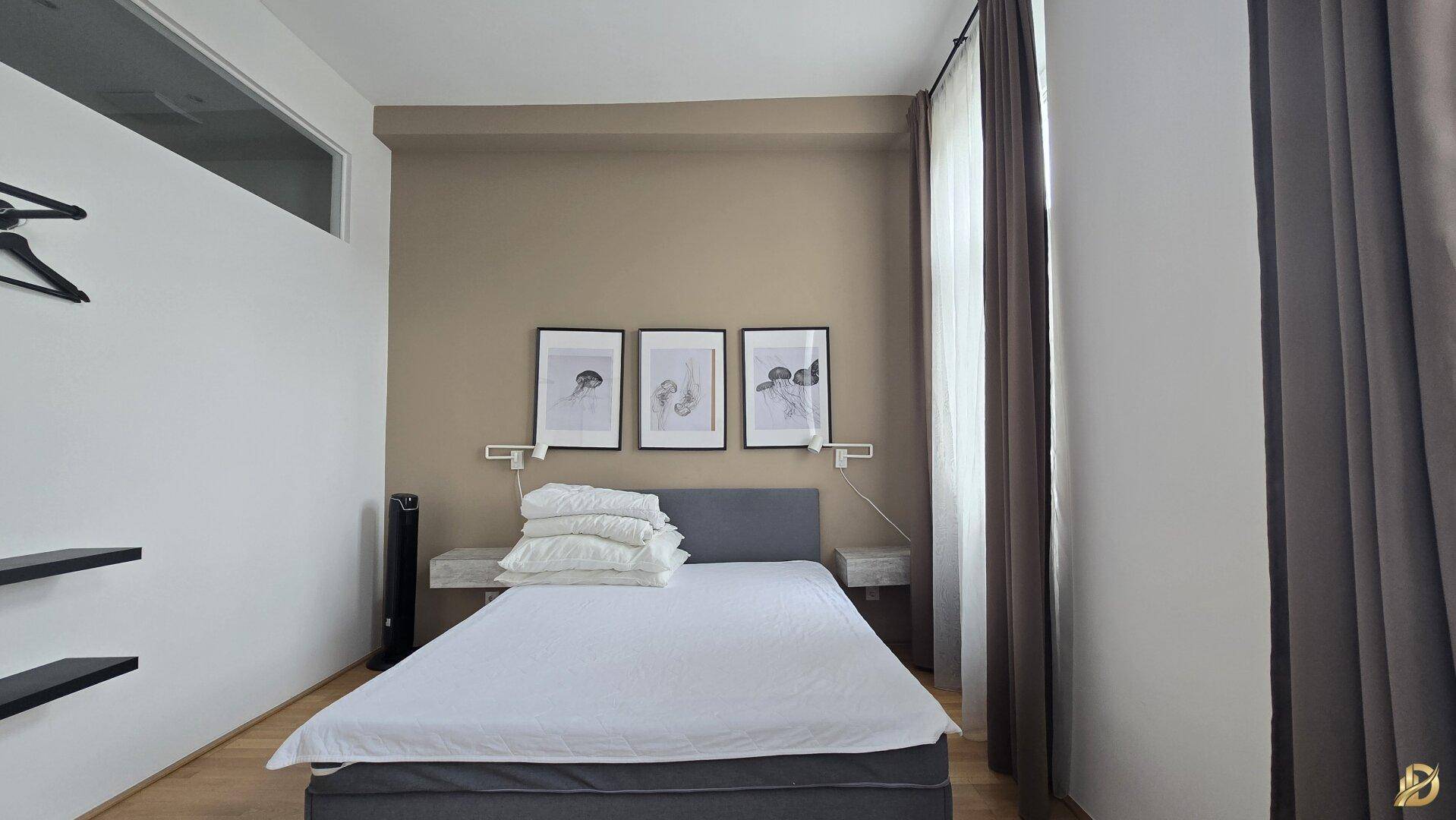 Helles Schlafzimmer mit Doppelbett, Parkettboden und einem Oberlicht, das den Raum erhellt.
