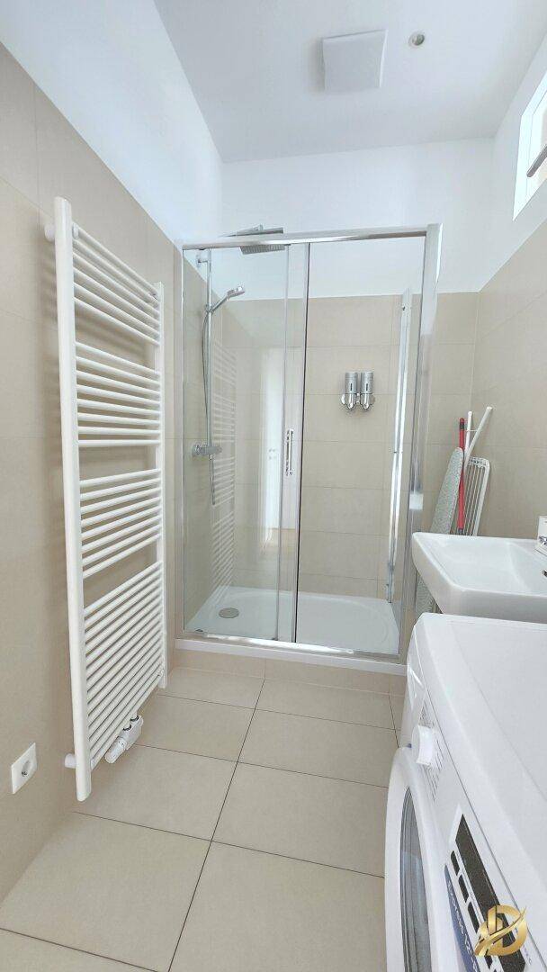 Modernes Badezimmer mit Duschkabine, Waschbecken und einem beheizten Handtuchhalter.