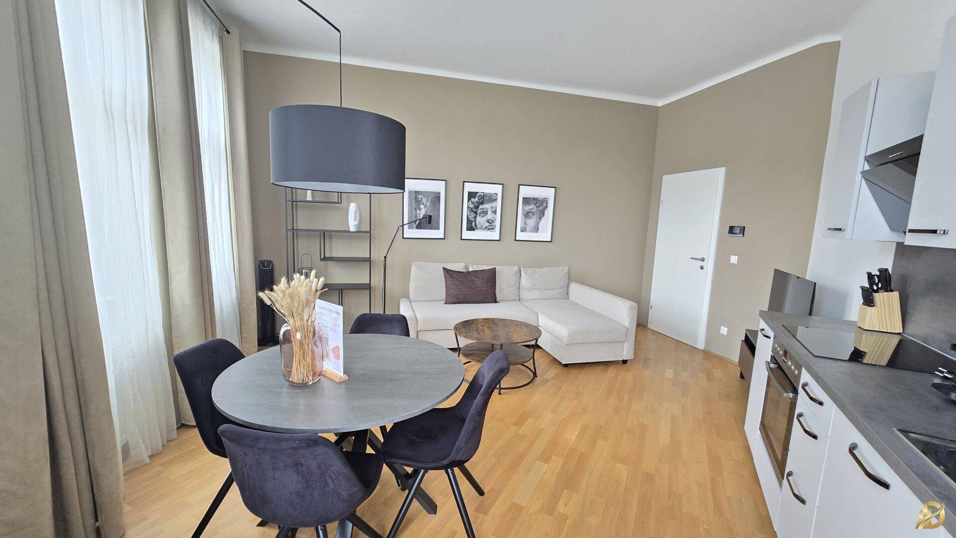 Essbereich mit rundem Tisch und Blick auf das helle Wohnzimmer mit Sofa und moderner Einrichtung.