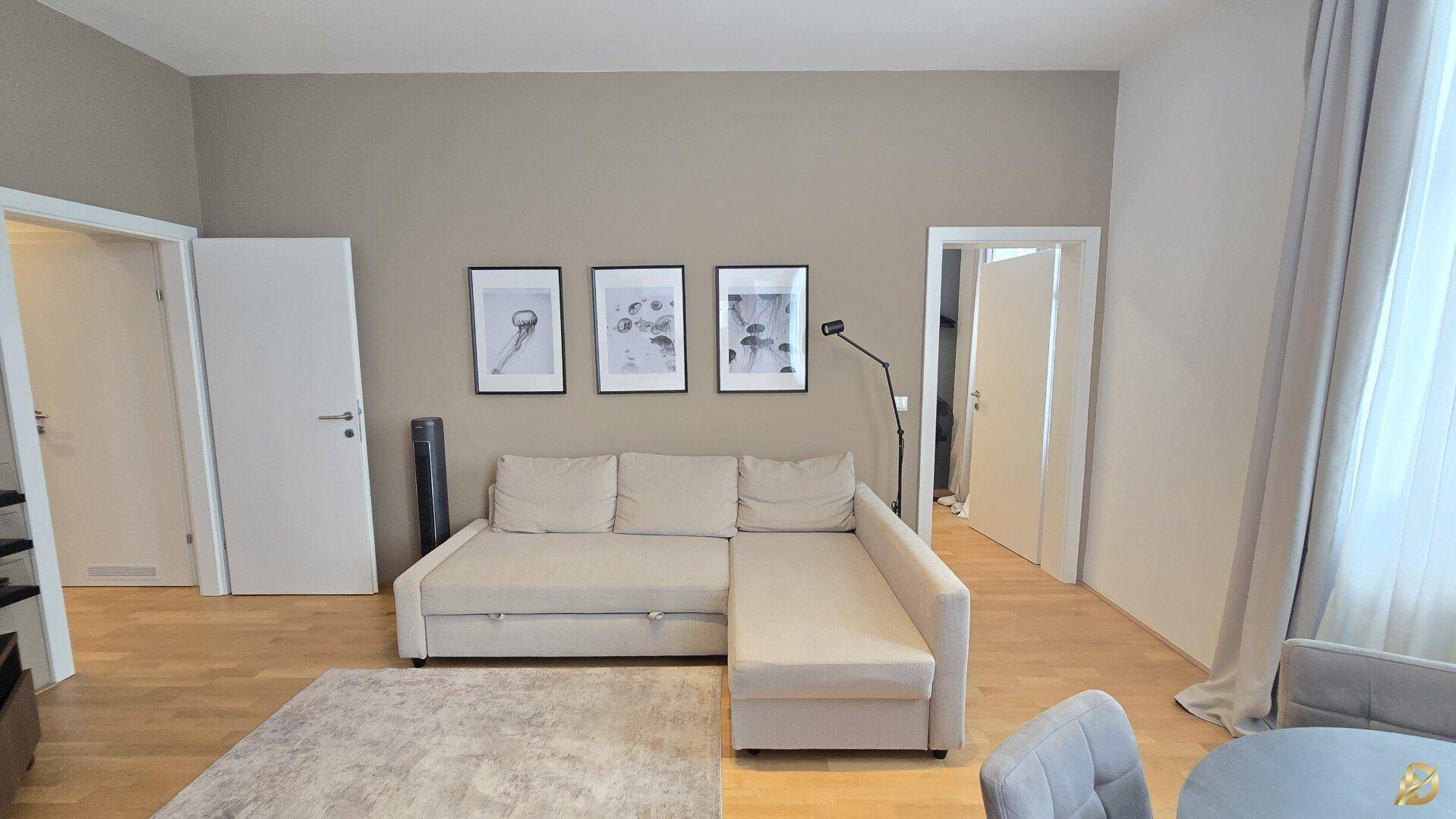 Heller Wohnbereich mit beigem Ecksofa, Holzboden und modernen Wandbildern.
