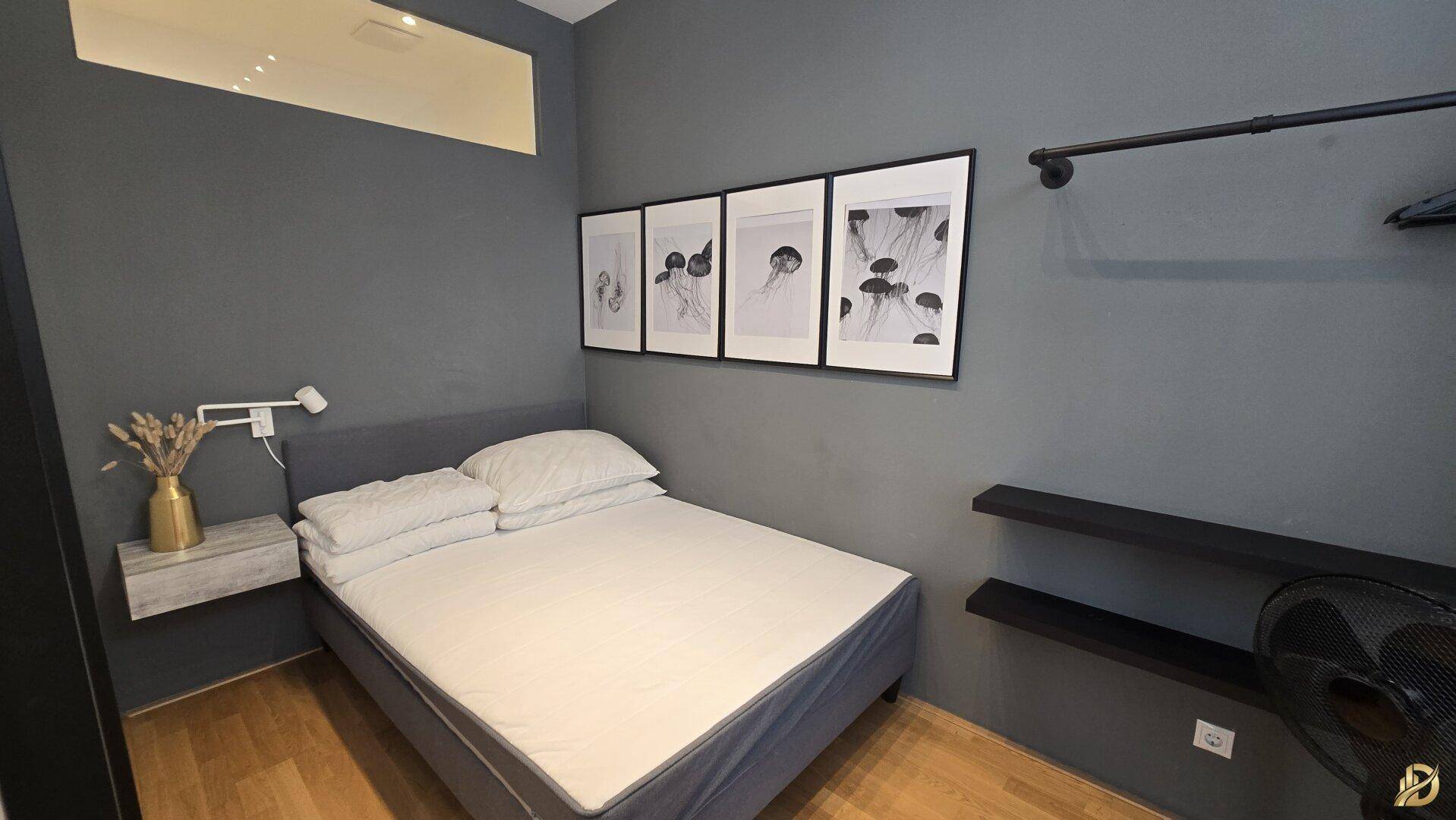 Schlafzimmer mit Doppelbett, dunklen Wänden und minimalistischer Einrichtung.