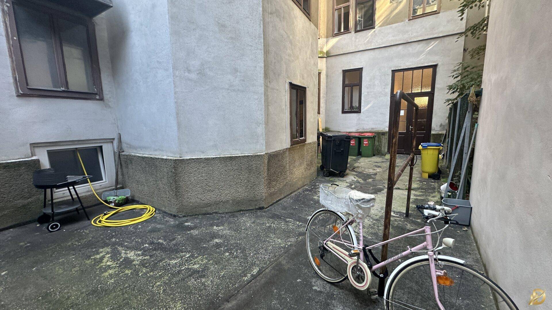 Innenhof mit Fahrrad, Grill und Zugang zu den Gebäudeeingängen.