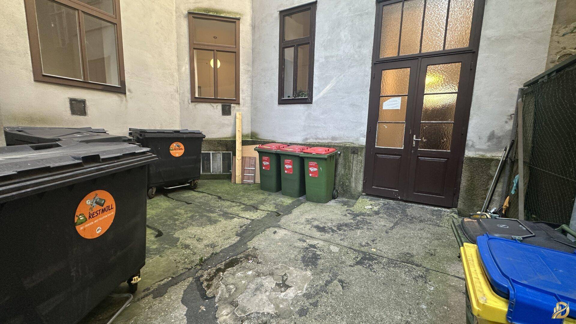 Innenhofbereich mit Mülltonnen und Gebäudefassaden.