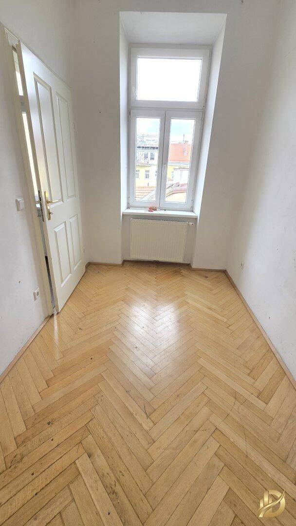 Gemütliches Zimmer mit Fischgrätparkett und einem Fenster, das viel Tageslicht hereinlässt.