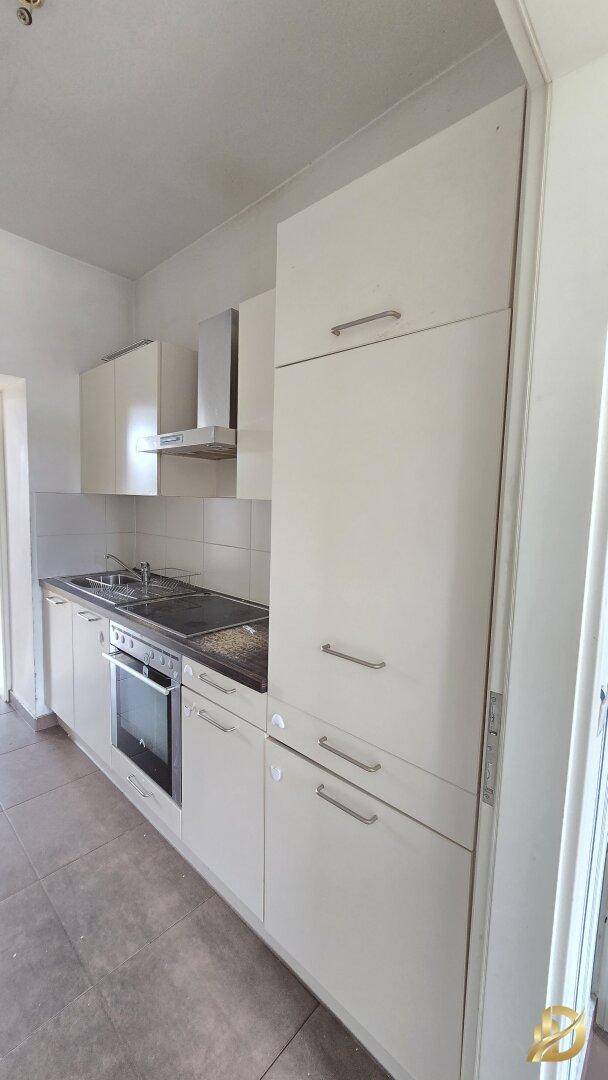 Moderne Küche mit weißen Hochglanzfronten, integriertem Backofen und Dunstabzugshaube.