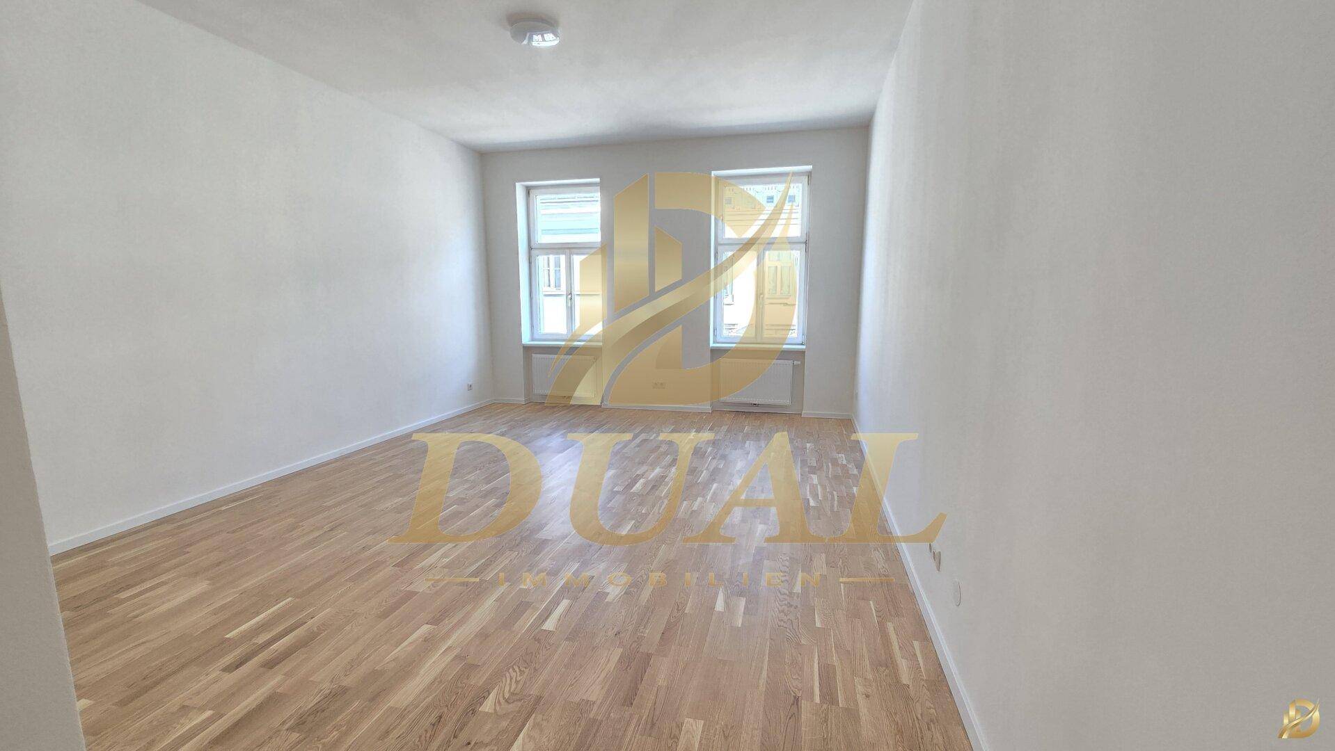 Geräumiges, helles Zimmer mit Holzboden und zwei großen Fenstern.
