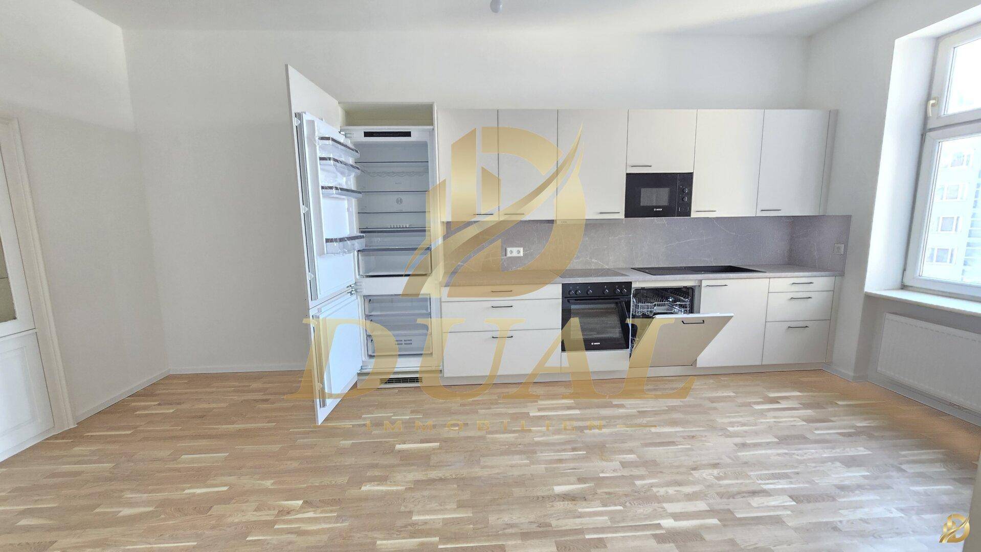 Moderne Einbauküche mit Kühlschrank, Geschirrspüler und Holzboden.