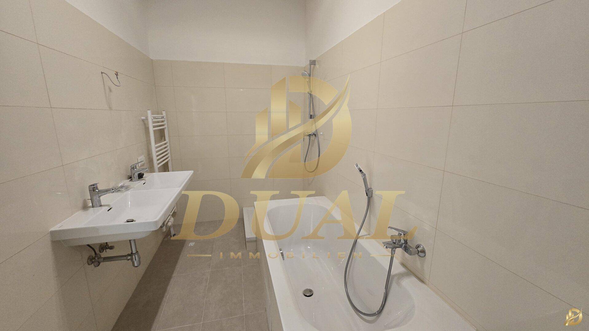 Helles Badezimmer mit Badewanne, Waschbecken und beigefarbenen Fliesen.