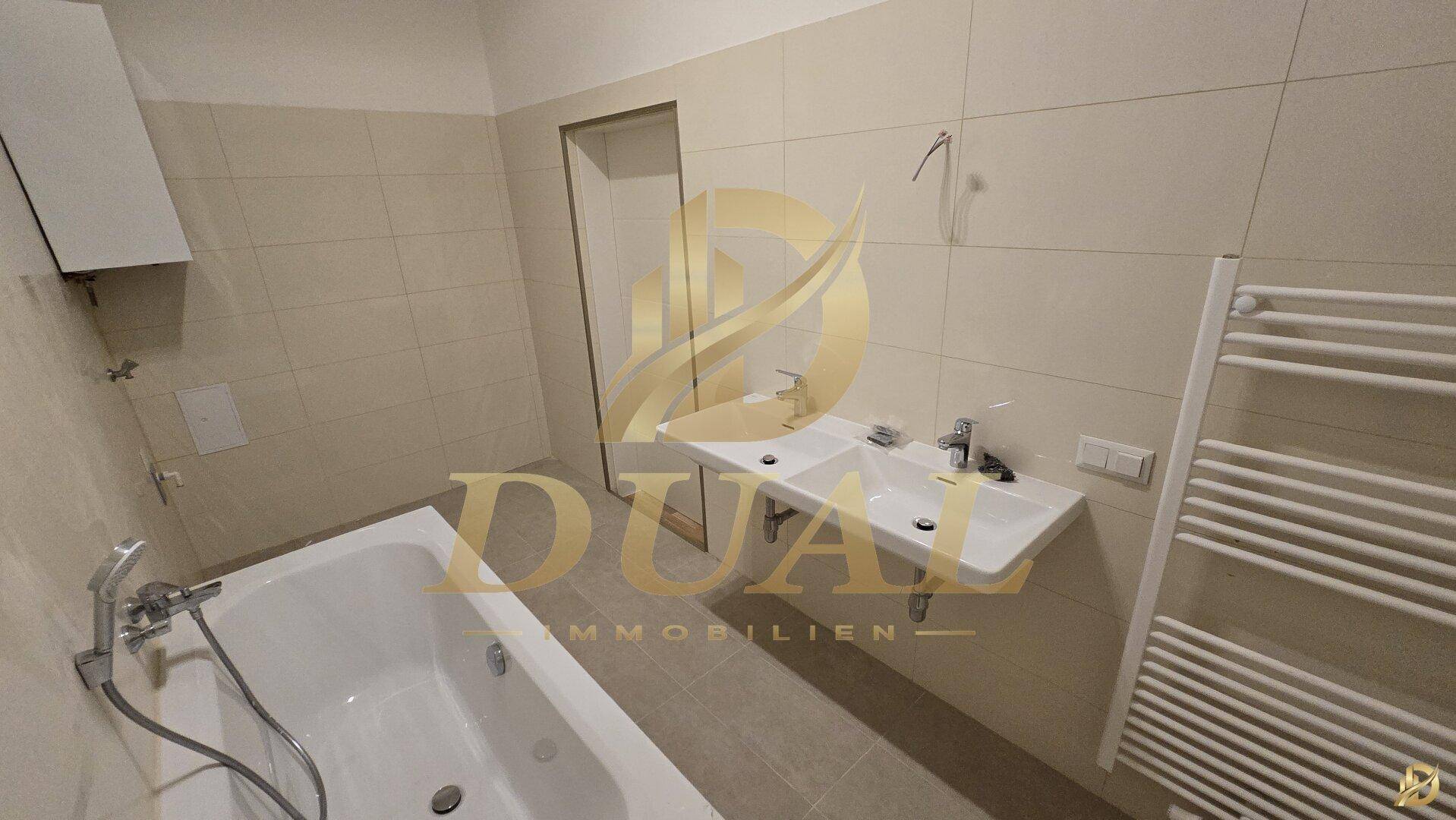 Badezimmer mit Badewanne, Doppelwaschbecken und beheiztem Handtuchhalter.