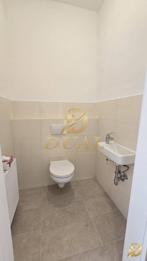 Modernes Gäste-WC mit wandhängender Toilette und kleinem Waschbecken.