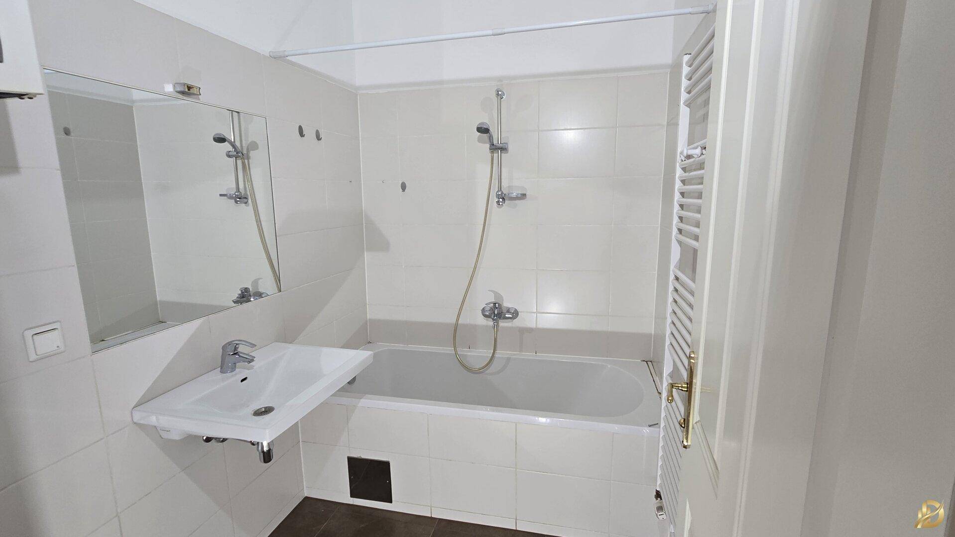 Funktionales Badezimmer mit Badewanne, Waschbecken und weiß gefliesten Wänden.
