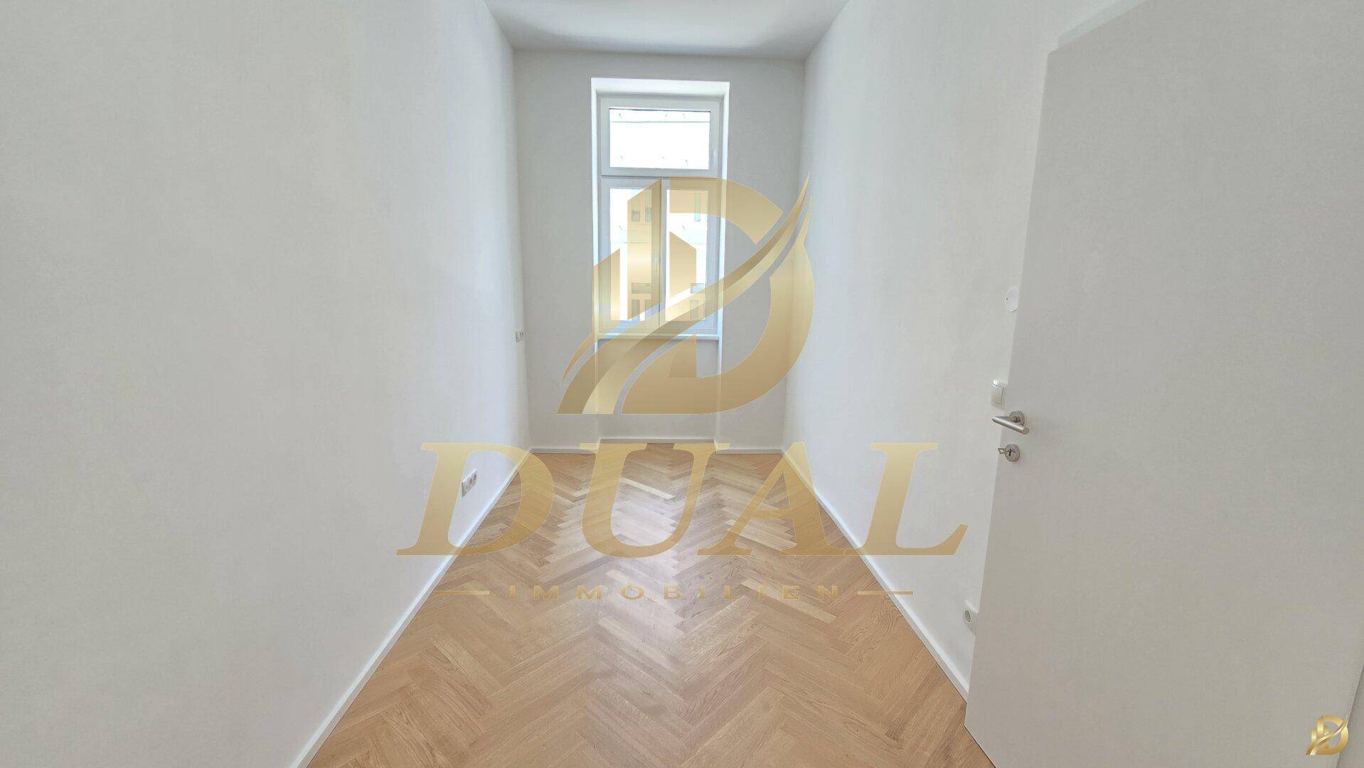 Schmaler, heller Raum mit Fischgrätparkett und einem Fenster, ideal als Schlaf- oder Arbeitszimmer.
