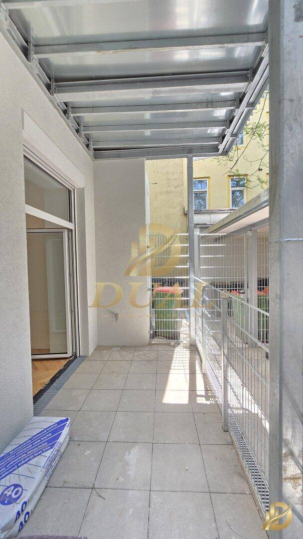 Überdachter Balkon mit Fliesenboden und Metallgeländer, ideal für entspannte Stunden im Freien.