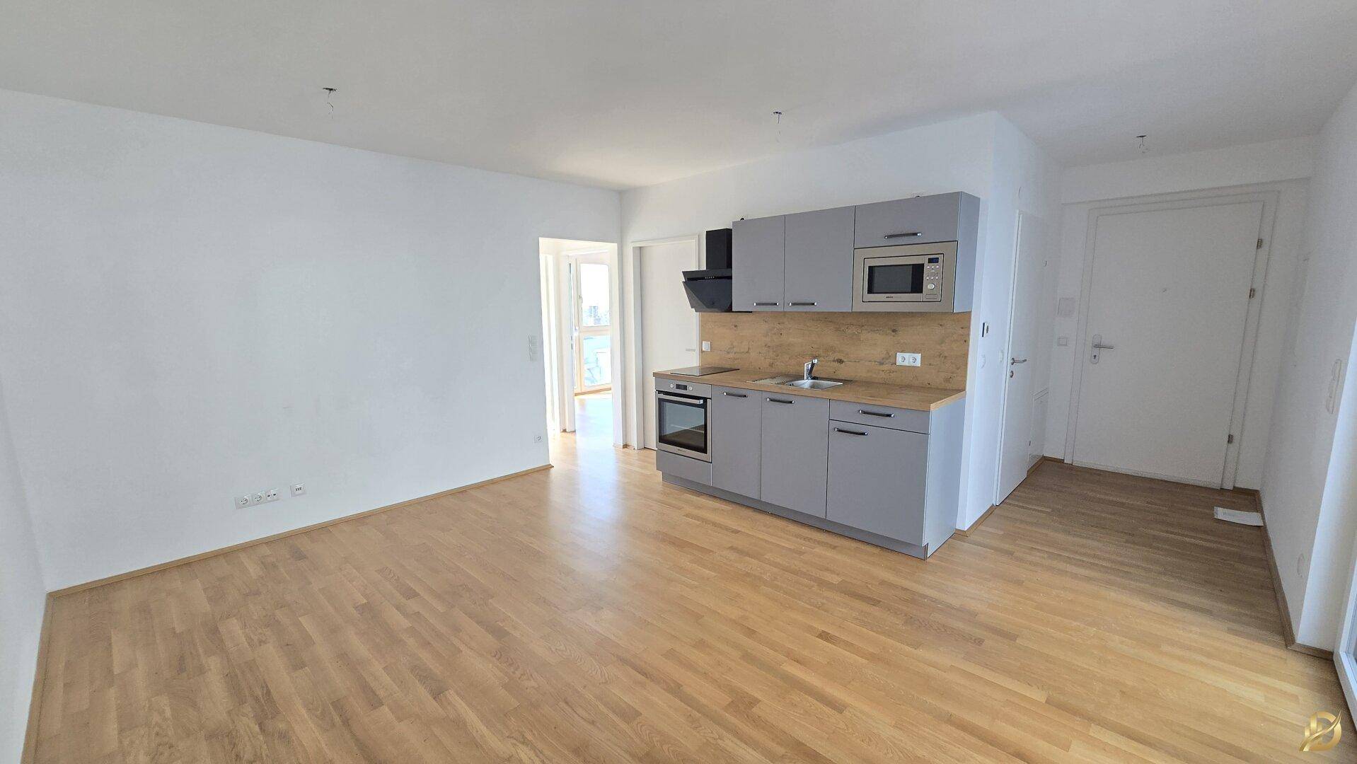 Geräumiger Wohnbereich mit moderner Küchenzeile und hellem Holzfußboden.