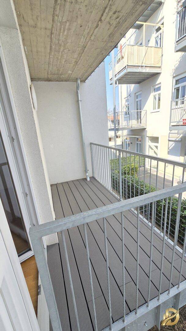 Schmaler Balkon mit modernem Bodenbelag und Blick auf die angrenzenden Gebäude.