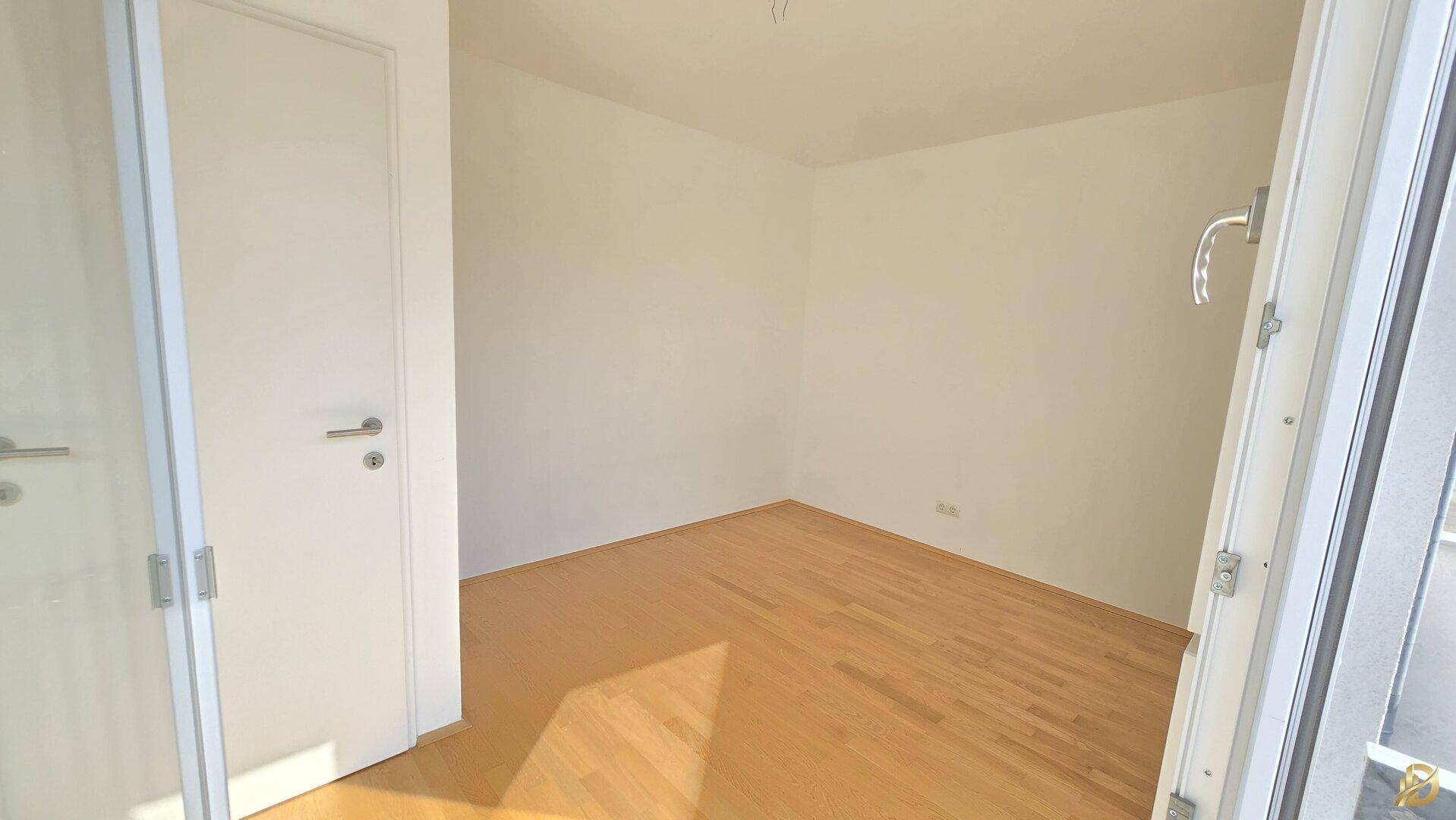 Leeres Zimmer mit Holzboden und Fenster, das viel Tageslicht bietet.