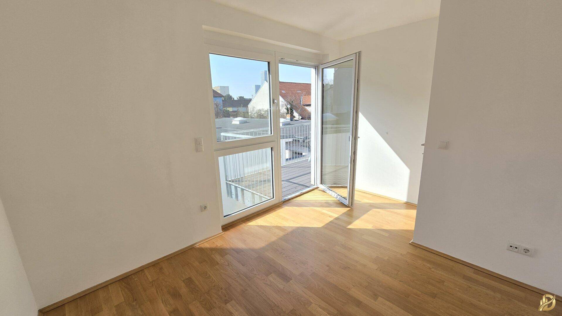 Helles Zimmer mit geöffneter Balkontür, die viel Sonnenlicht hereinlässt.
