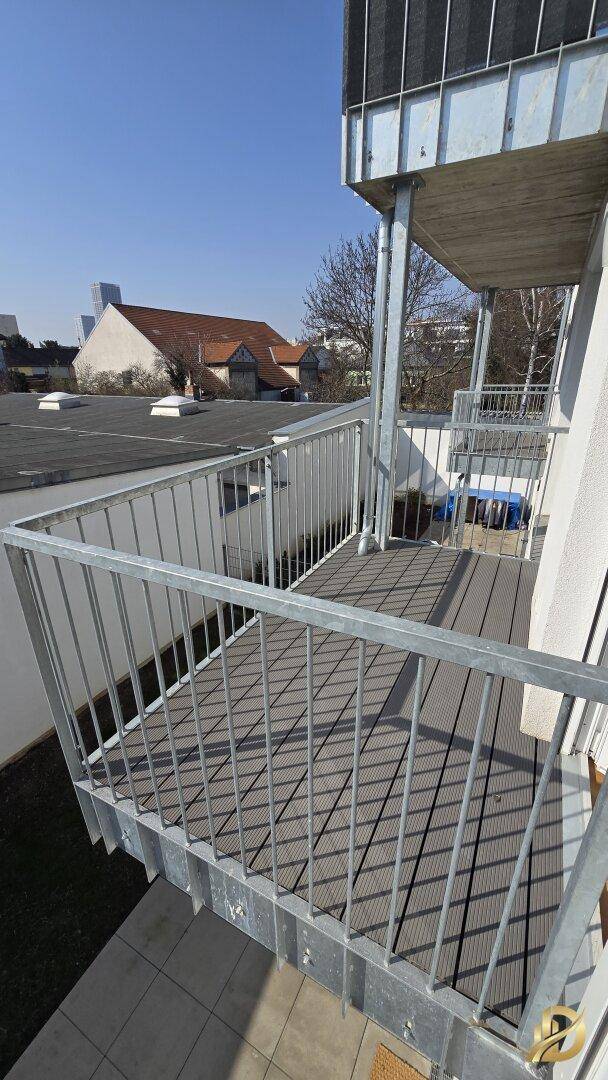 Geräumiger Balkon mit grauem Dielenboden und Blick auf die Umgebung.