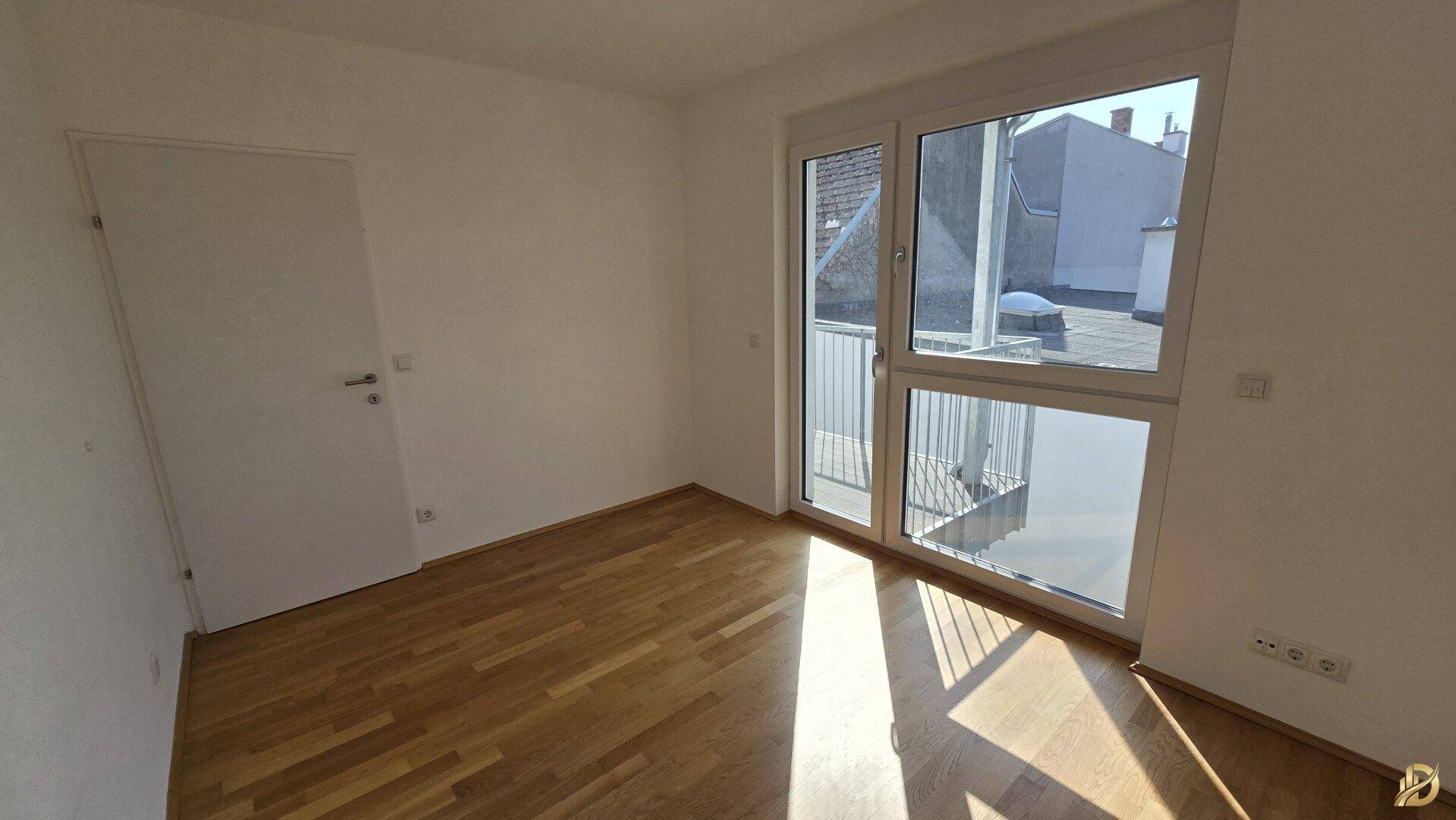 Lichtdurchflutetes Zimmer mit Parkettboden und Balkontür, ideal als Schlafzimmer.