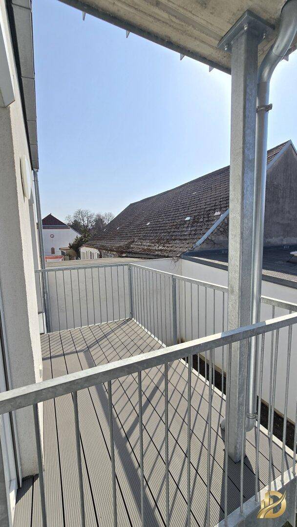 Heller Balkon mit modernem Bodenbelag und Metallgeländer, sonniger Ausblick.