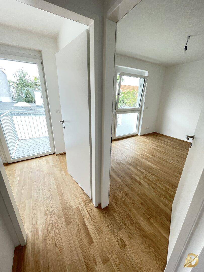 Heller Flur mit Holzboden, der zu verschiedenen Zimmern führt.