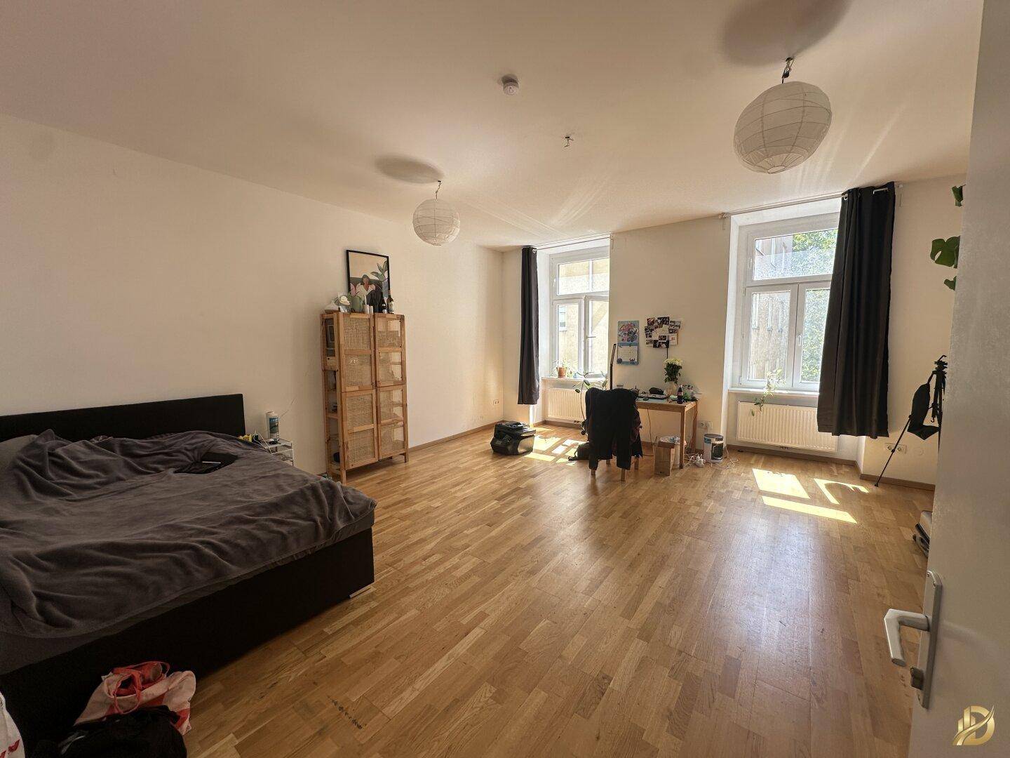 Geräumiges Schlafzimmer mit Holzboden, großem Bett und viel natürlichem Licht.