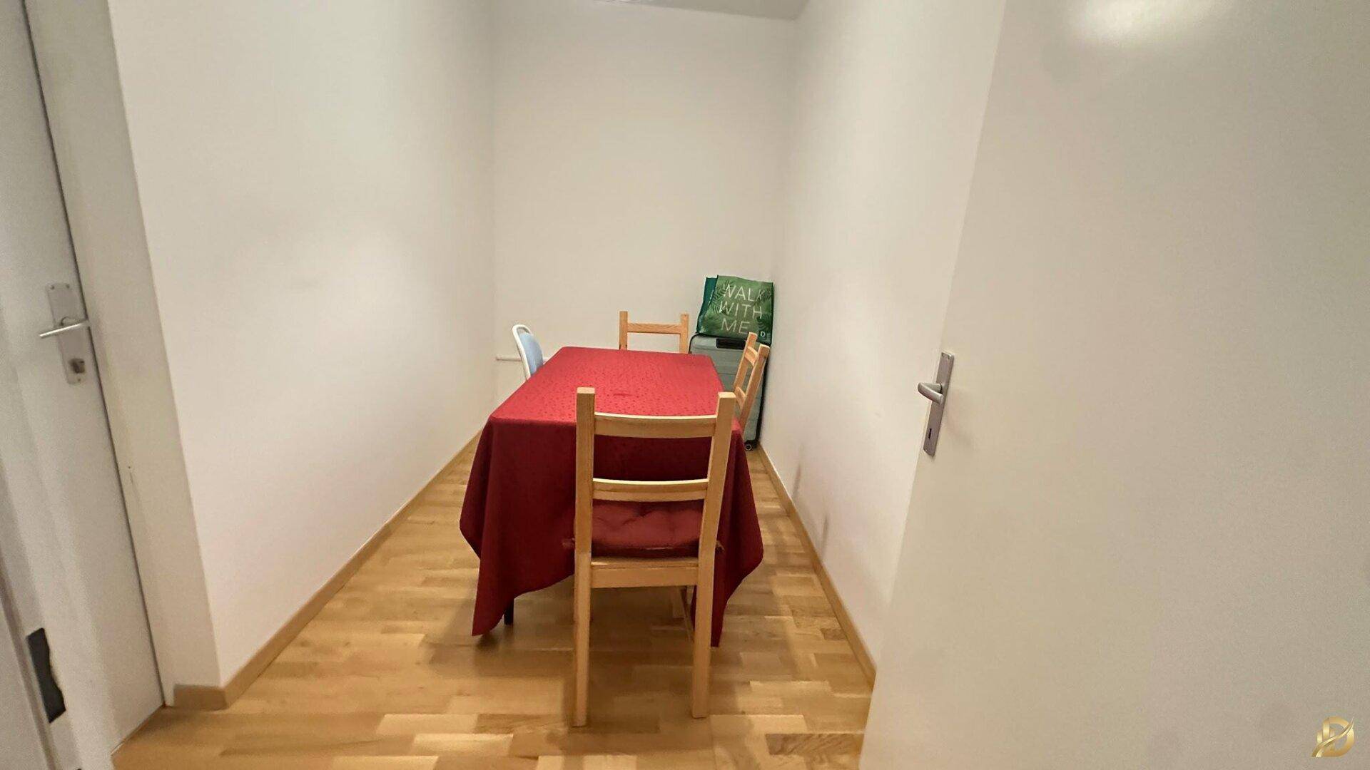 Kleiner Essbereich mit Holztisch, roter Tischdecke und Holzstühlen.