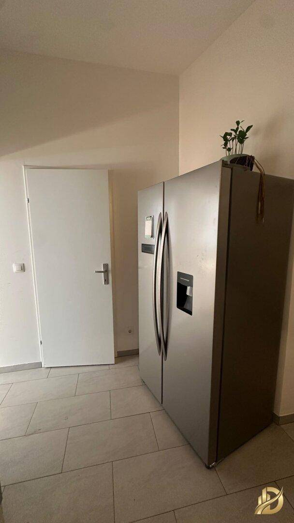 Großer amerikanischer Kühlschrank aus Edelstahl neben einer weißen Tür.