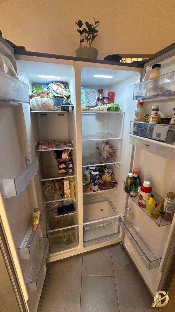 Gut gefüllter, sauberer amerikanischer Kühlschrank mit Doppeltüren und Eiswürfelspender.