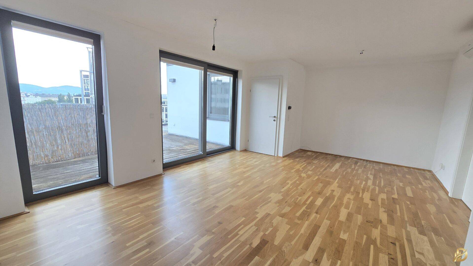 Helles Wohnzimmer mit Holzboden und Zugang zu einer großen Terrasse, bietet viel Tageslicht.